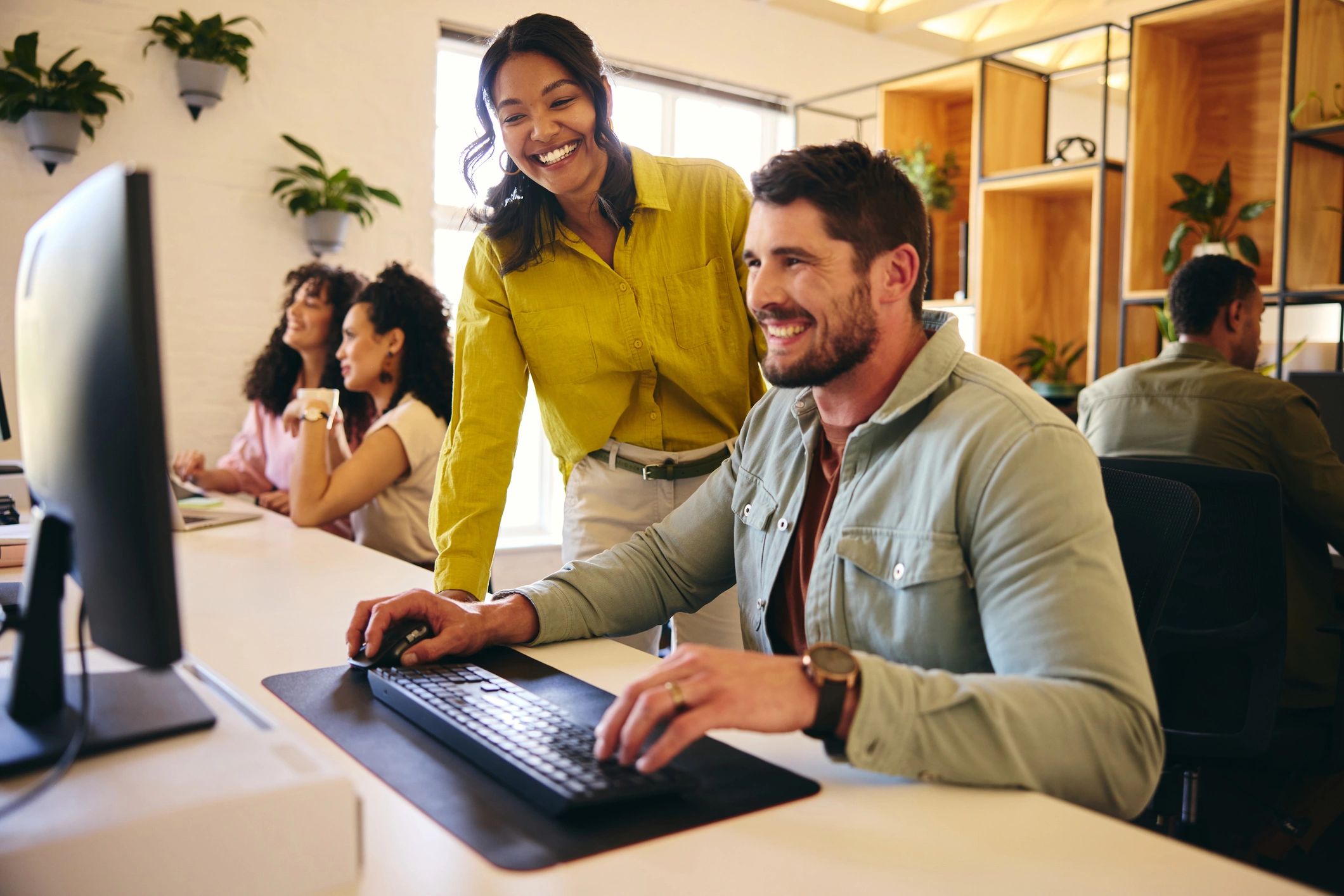 Customer support colleagues collaborating at a desktop computer